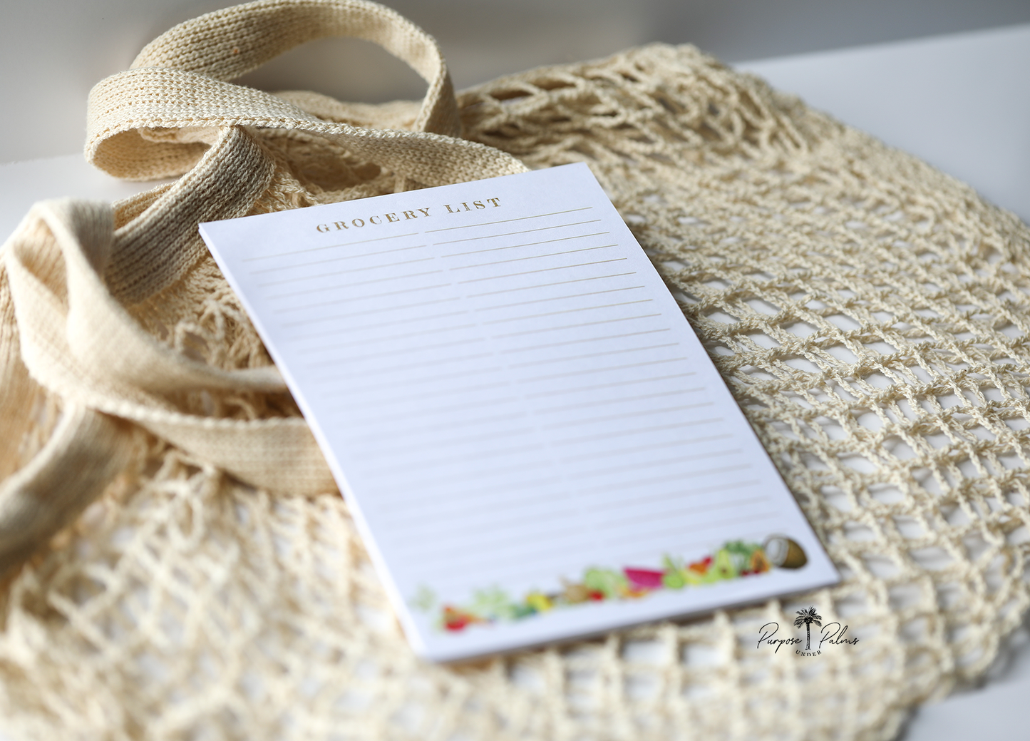 white grocery list notepad with grocery list at the top and two lined columns. watercolor fruits and vegetables at the bottom.