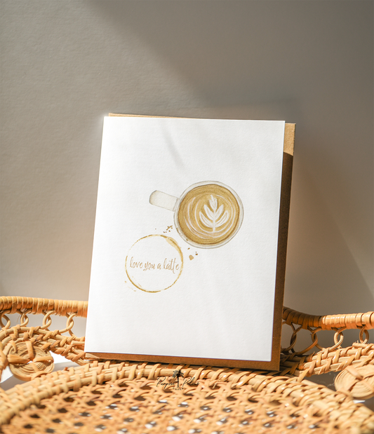 white greeting card with watercolor painting of coffee mug and a coffee ring stain with love you a latte in the middle. love you a latte greeting card. Kraft envelope.